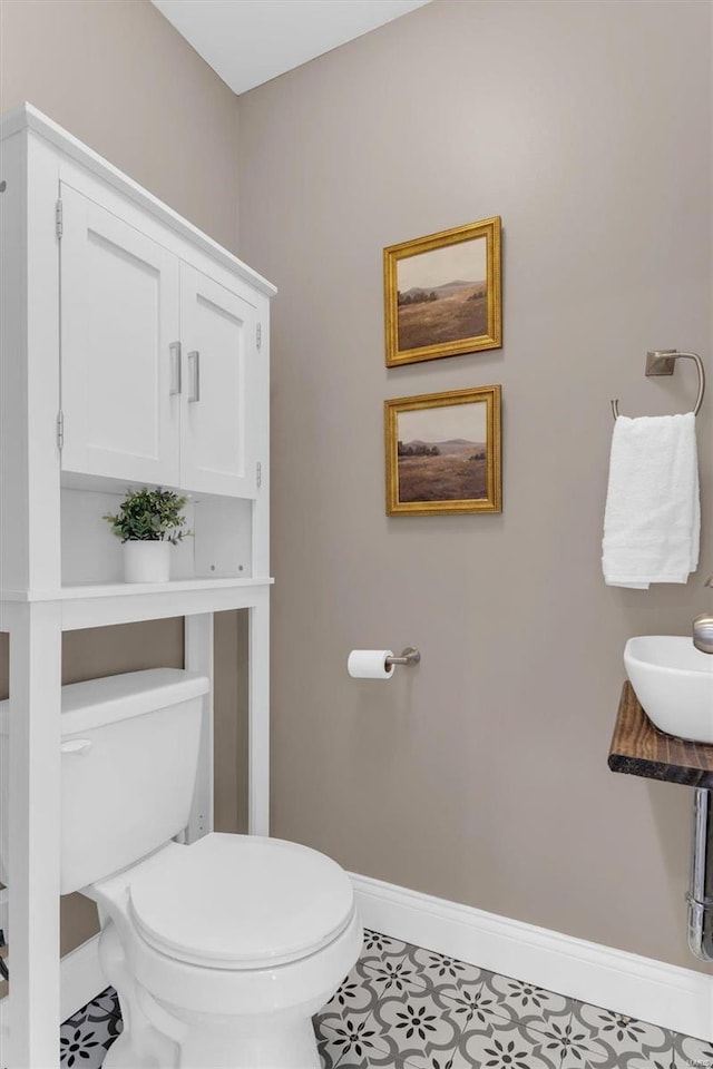 bathroom featuring a sink, baseboards, and toilet