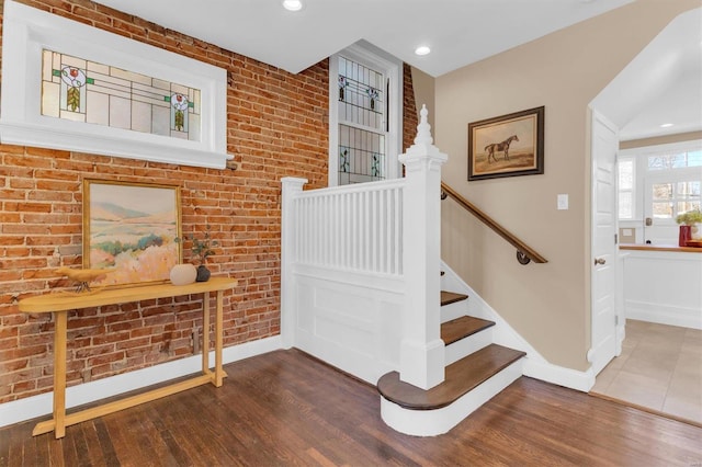 stairs with recessed lighting, brick wall, baseboards, and wood finished floors