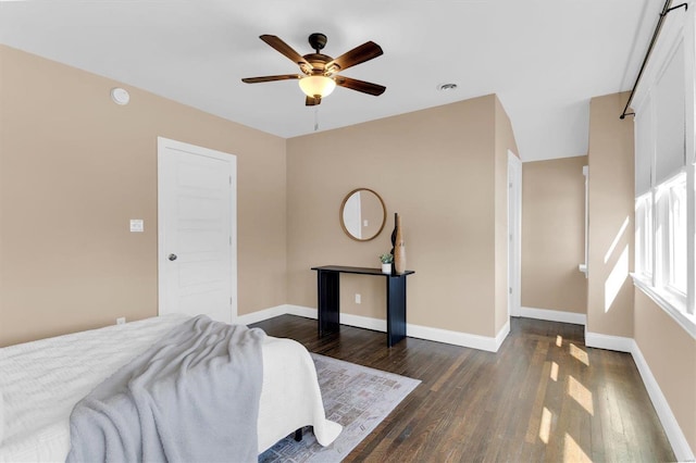 bedroom featuring baseboards, dark wood finished floors, and a ceiling fan