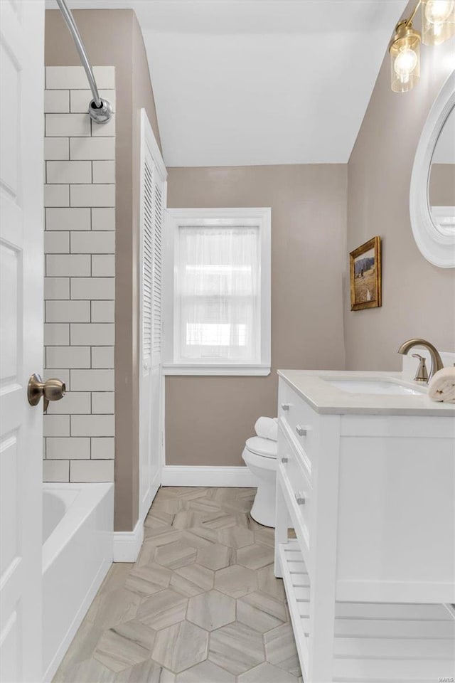 bathroom with vanity, toilet, tub / shower combination, and baseboards