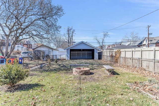 view of yard with an outdoor fire pit, a detached garage, an outdoor structure, and fence