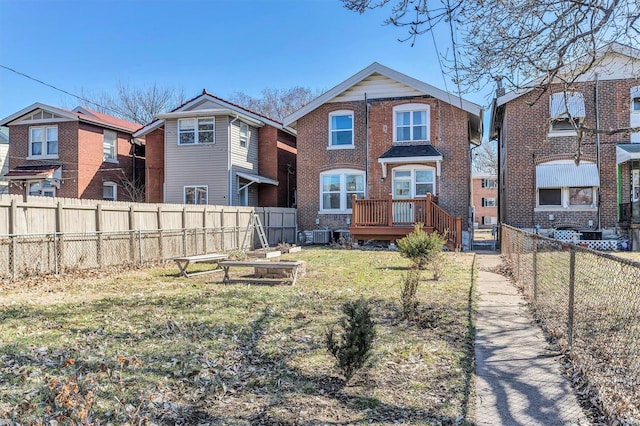 rear view of property with a garden, a fenced backyard, brick siding, and a lawn