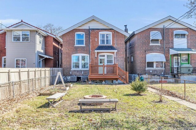 rear view of property with brick siding, a fire pit, a lawn, and fence private yard