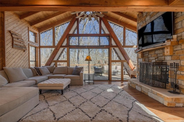 living area with beam ceiling, a fireplace, ceiling fan, wood finished floors, and wooden ceiling