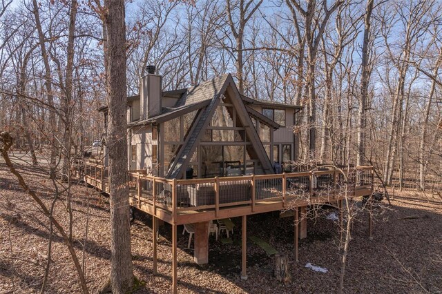 back of property featuring stairs, a chimney, and a deck