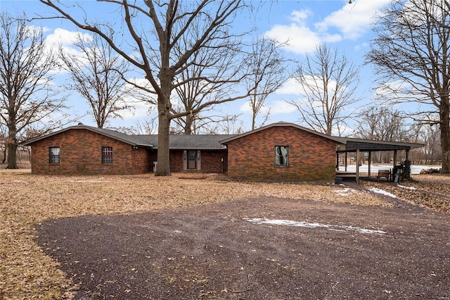 view of front of property with driveway, an attached carport, and brick siding