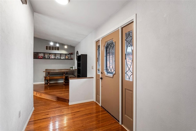 foyer with lofted ceiling, hardwood / wood-style flooring, visible vents, and baseboards