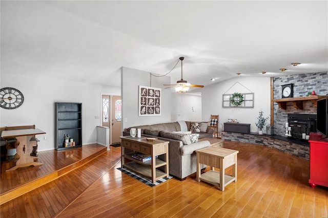 living room with a ceiling fan, lofted ceiling, wood-type flooring, and a fireplace