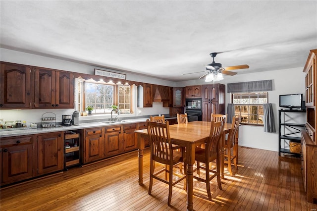 interior space featuring light countertops, a sink, light wood-type flooring, premium range hood, and black appliances