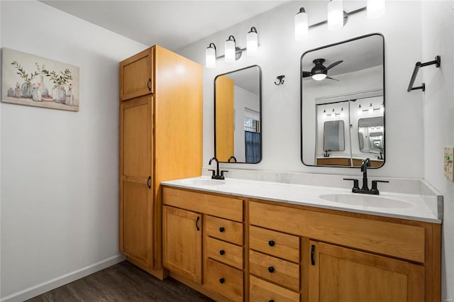 bathroom featuring wood finished floors, a sink, a ceiling fan, and baseboards