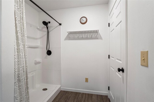 bathroom with curtained shower, baseboards, and wood finished floors