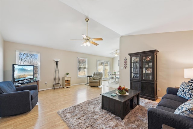 living area featuring vaulted ceiling, ceiling fan, light wood-style flooring, and baseboards