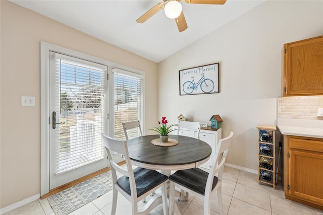 dining space with vaulted ceiling, ceiling fan, light tile patterned flooring, and baseboards