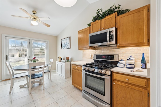 kitchen with stainless steel appliances, light countertops, vaulted ceiling, and decorative backsplash