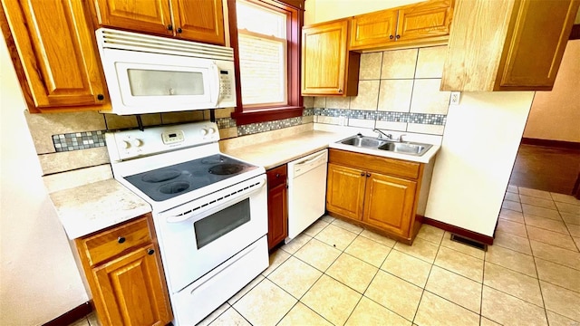 kitchen featuring white appliances, light countertops, a sink, and backsplash