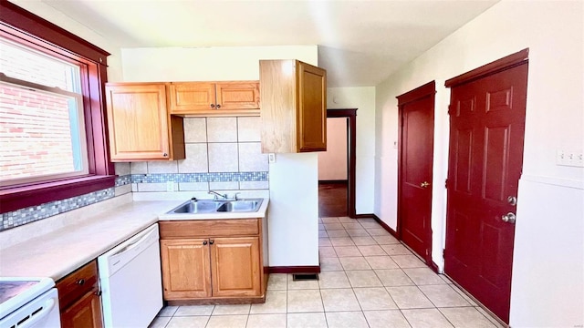 kitchen featuring decorative backsplash, stove, white dishwasher, a sink, and light tile patterned flooring