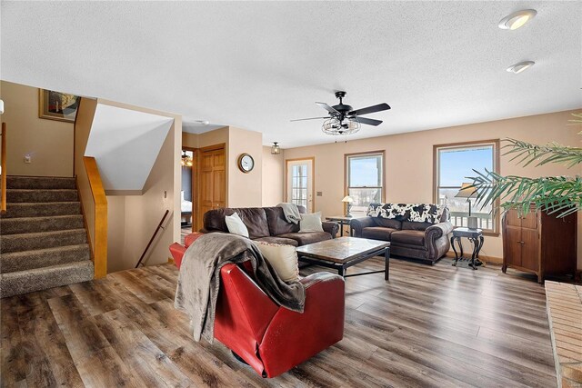 living room with stairs, ceiling fan, wood finished floors, and a textured ceiling