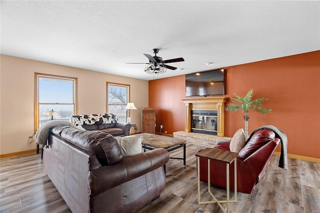 living area with baseboards, a textured ceiling, wood finished floors, and a fireplace