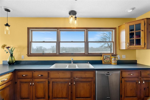 kitchen featuring a sink, stainless steel dishwasher, dark countertops, and brown cabinetry