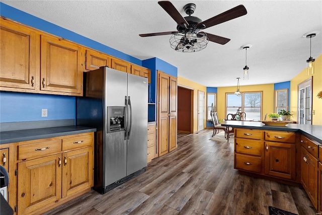 kitchen featuring dark countertops, dark wood finished floors, brown cabinetry, and stainless steel fridge with ice dispenser