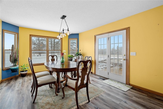 dining area with a wealth of natural light, a textured ceiling, and wood finished floors