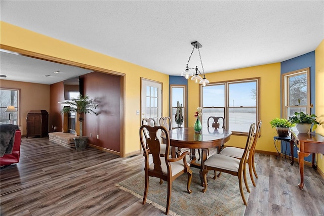 dining room featuring baseboards, a textured ceiling, and wood finished floors