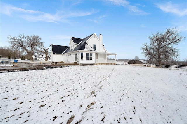 snow covered house with fence and a chimney