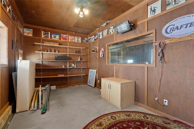 basement featuring wood walls and ceiling fan