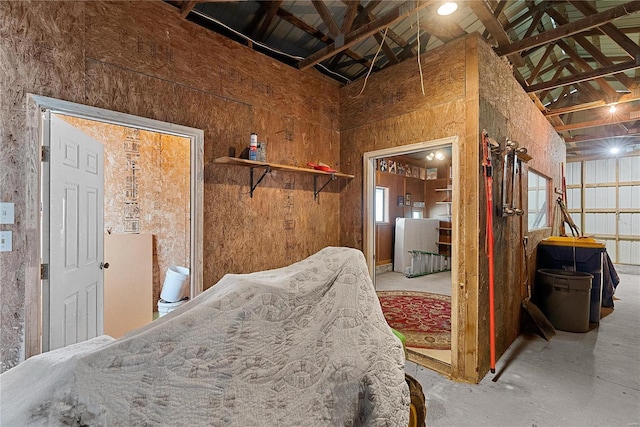 miscellaneous room featuring unfinished concrete flooring and a high ceiling