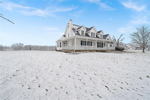 snow covered property featuring a porch and a chimney