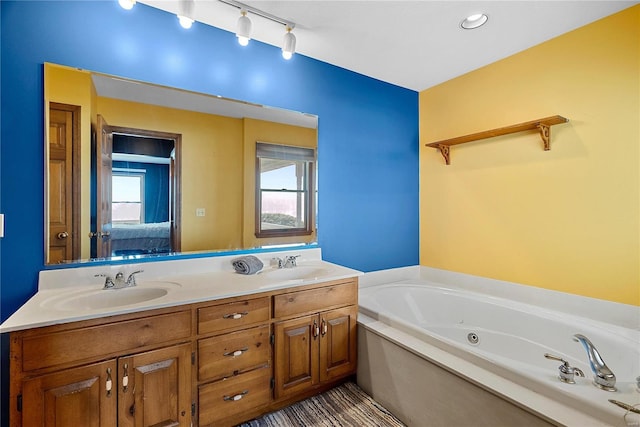 bathroom featuring double vanity, a jetted tub, connected bathroom, and a sink