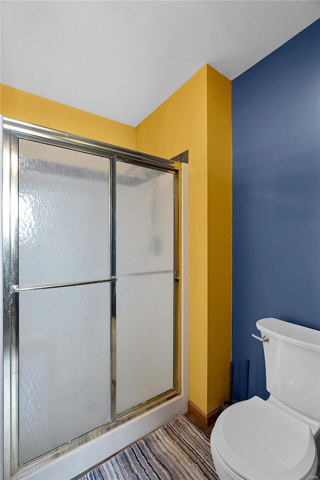 bathroom featuring baseboards, toilet, and a shower stall