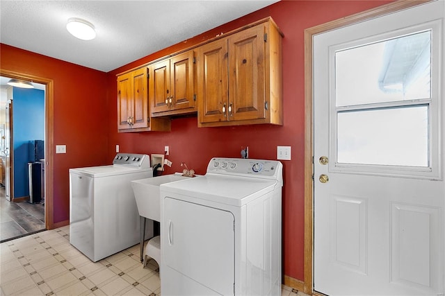 laundry room with a sink, cabinet space, light floors, and washer and clothes dryer