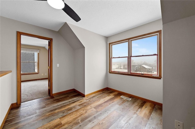 bonus room featuring visible vents, baseboards, a textured ceiling, and light wood-style flooring