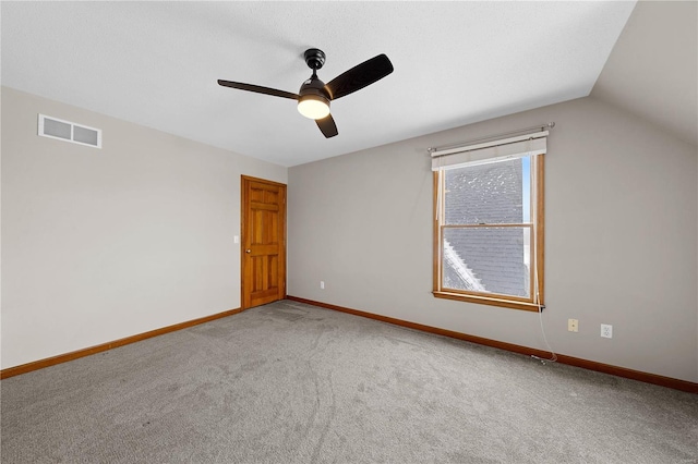 empty room featuring visible vents, baseboards, vaulted ceiling, carpet flooring, and a ceiling fan