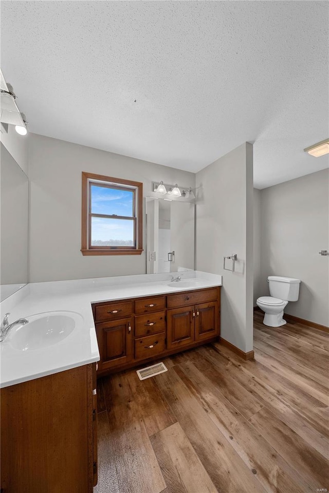 full bath featuring double vanity, wood finished floors, visible vents, and a sink