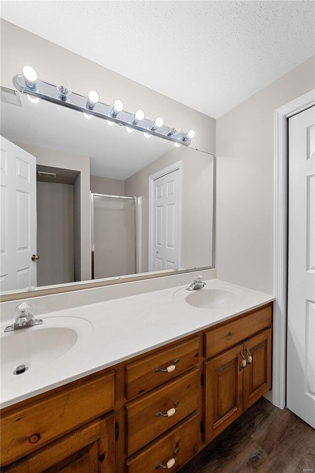 bathroom with a sink, visible vents, a textured ceiling, and double vanity