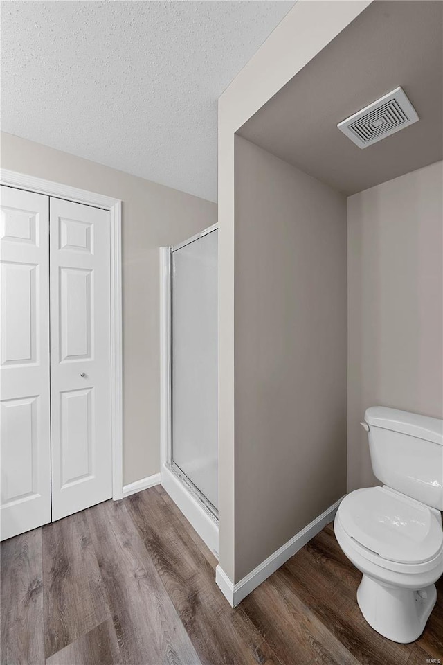 bathroom with visible vents, a stall shower, toilet, and wood finished floors