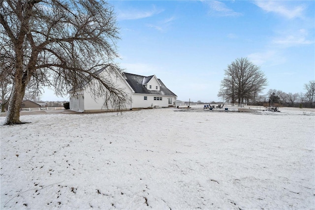 snowy yard featuring a garage and fence