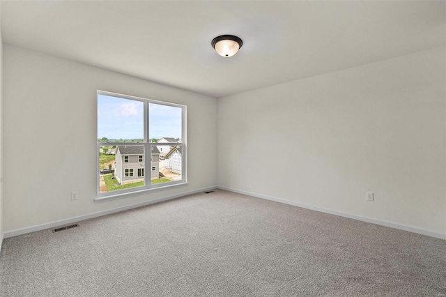 empty room featuring carpet, visible vents, and baseboards