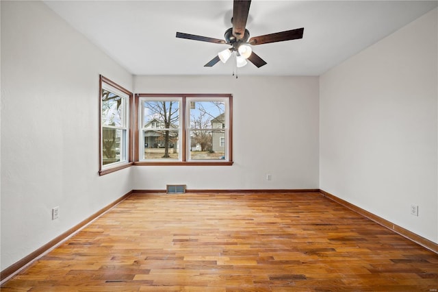 unfurnished room with baseboards, visible vents, ceiling fan, and wood finished floors