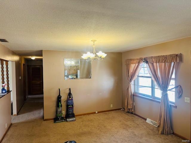 unfurnished dining area featuring carpet, a textured ceiling, visible vents, and a notable chandelier