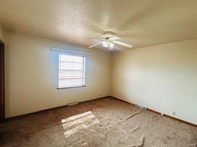 carpeted spare room featuring ceiling fan, a textured ceiling, and baseboards