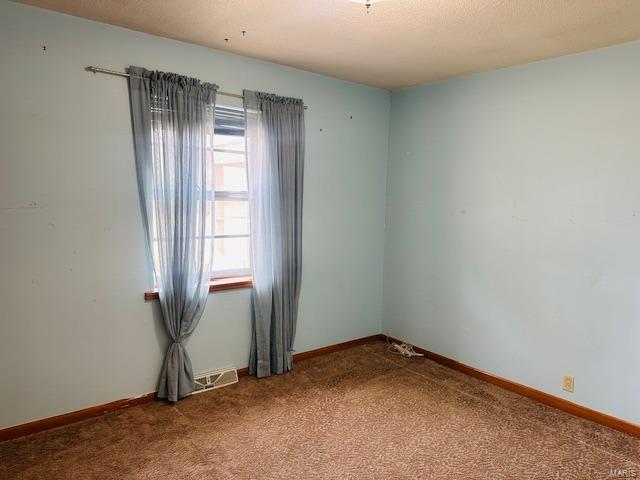 carpeted spare room with baseboards and a textured ceiling