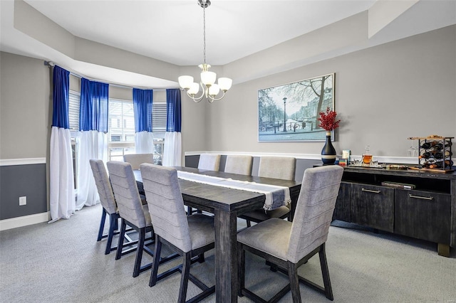 dining area featuring light carpet, a notable chandelier, and baseboards