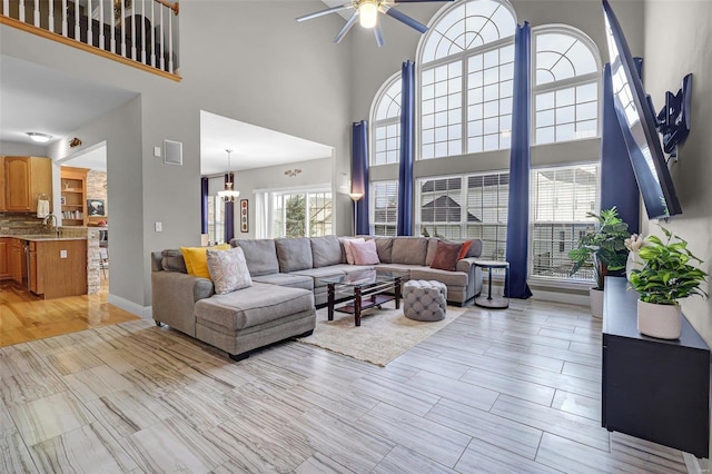 living room with a ceiling fan, light wood finished floors, and baseboards