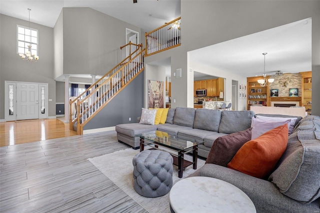 living room featuring built in features, a notable chandelier, light wood finished floors, baseboards, and stairs