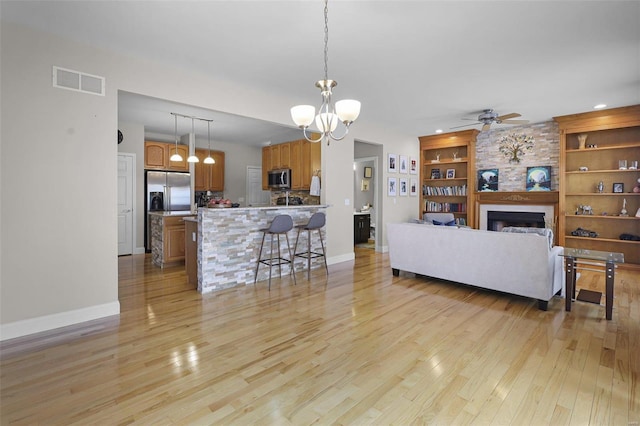 living area featuring light wood-type flooring, visible vents, a fireplace, and baseboards