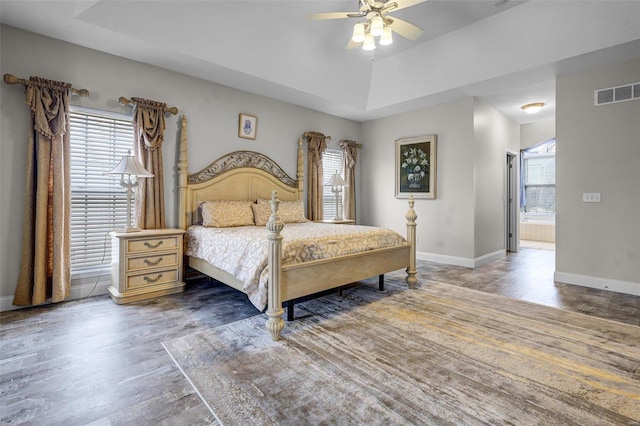 bedroom with wood finished floors, visible vents, baseboards, and multiple windows