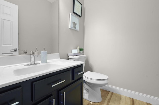 bathroom with toilet, baseboards, wood finished floors, and vanity